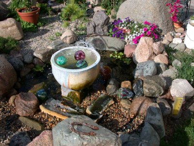 Blown ornaments floating in reitred crucible with fountain in rock garden at White Pine Studio
