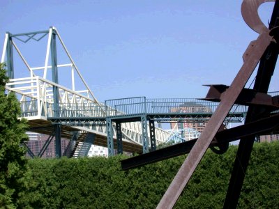 Artistic view of steel sculpture and pedestrian bridge over expressway