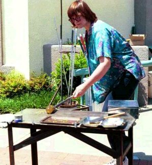 Diane working outdoors at Kittrell-Riffkind, gathering small lampworked flowers.